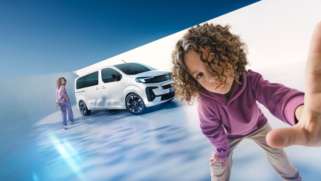  Kobieta i chłopiec z białym Oplem Zafirą Electric w tle